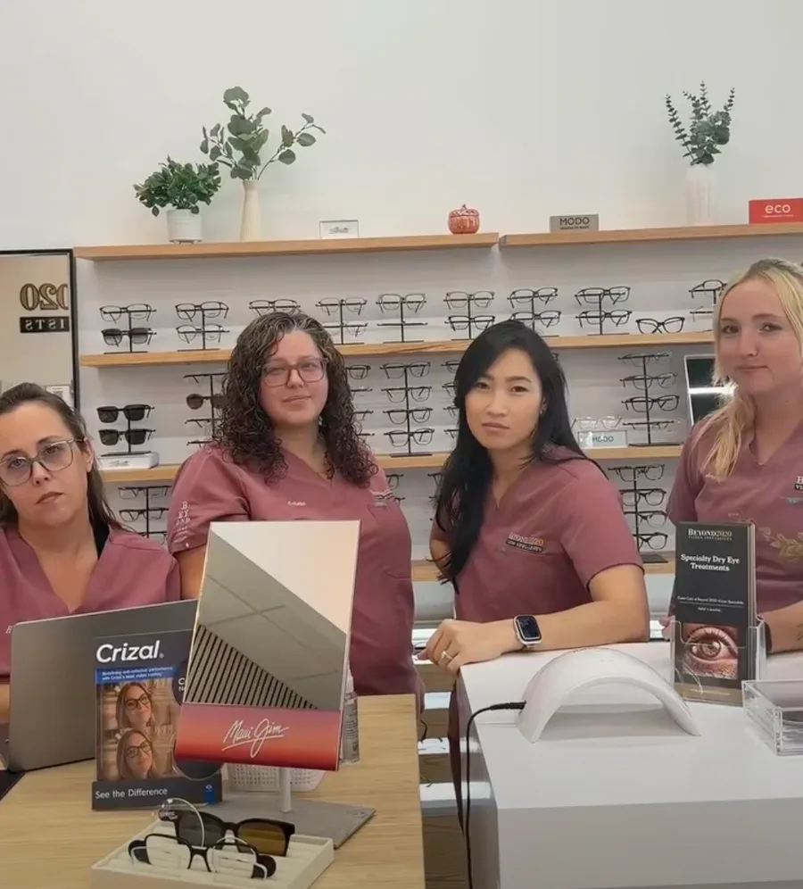 Four members of our team in matching pink scrubs giving the camera a deadpan look at the optical counter